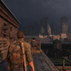 In an image from the game The Last of Us, Joel stands on a rooftop and in the distance, one skyscraper can be seen leaning against another.